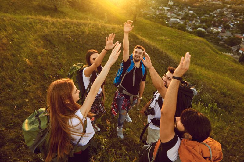 High,Angle,Of,Team,Of,Happy,Young,Tourists,Reaching,Out